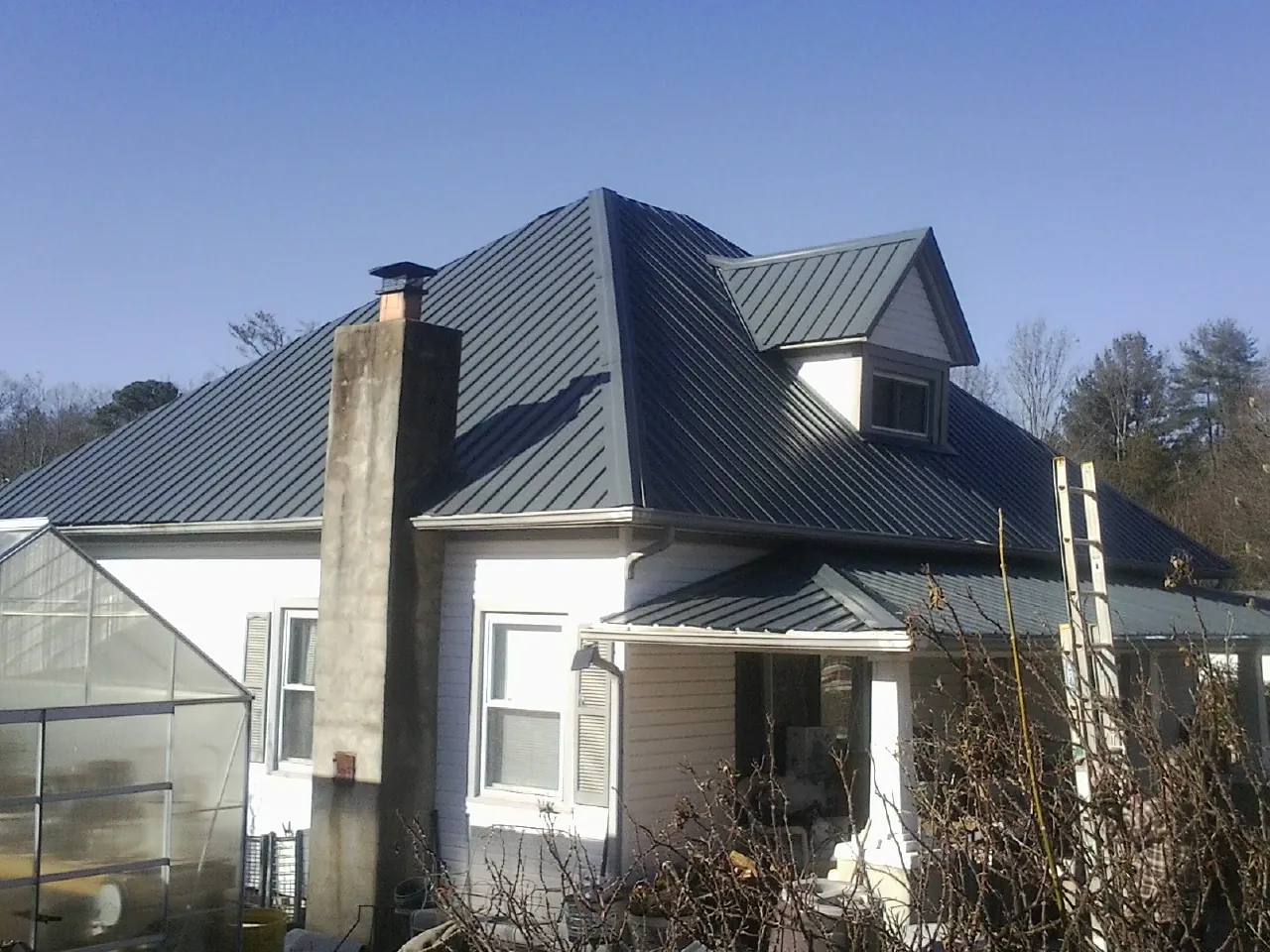 Dark blue standing seam metal roof on a white farmhouse with dormer — Slate & Tile Roof Repair by Roofing Brothers in Harrodsburg