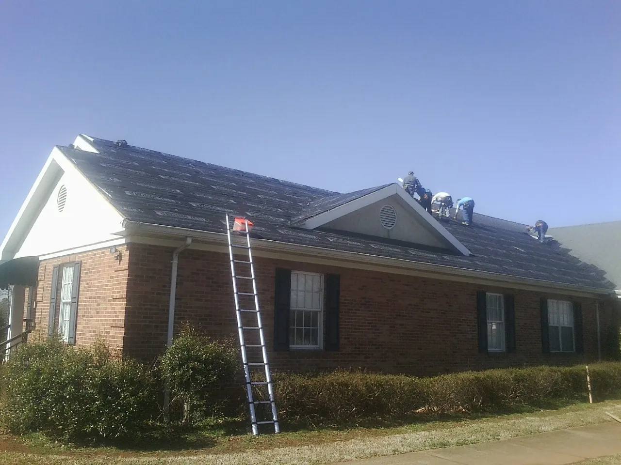 Crew tearing shingles off a brick ranch roof with a ladder set — Metal Roof Repair work by our crew in Harrodsburg