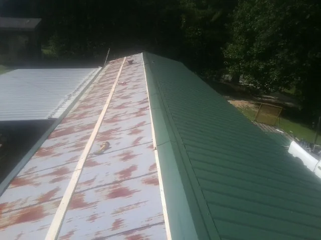 Old rusted panels beside newly installed green metal roofing — Wind Damage Roof Repair by Roofing Brothers in Harrodsburg
