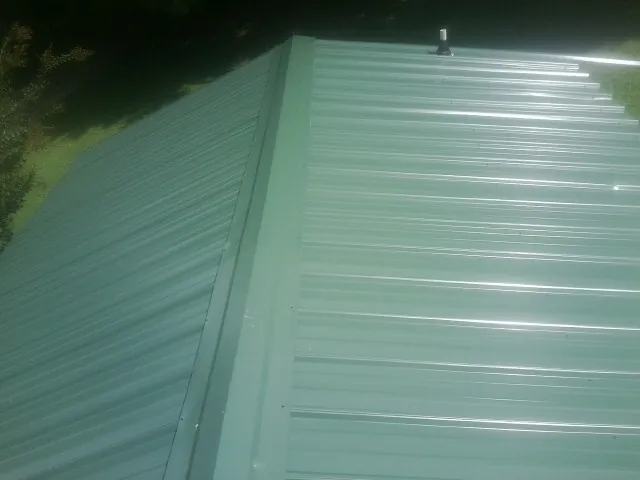 New green metal panels meeting at the ridge of a roof — Flat Roof Repair work by our crew in Harrodsburg