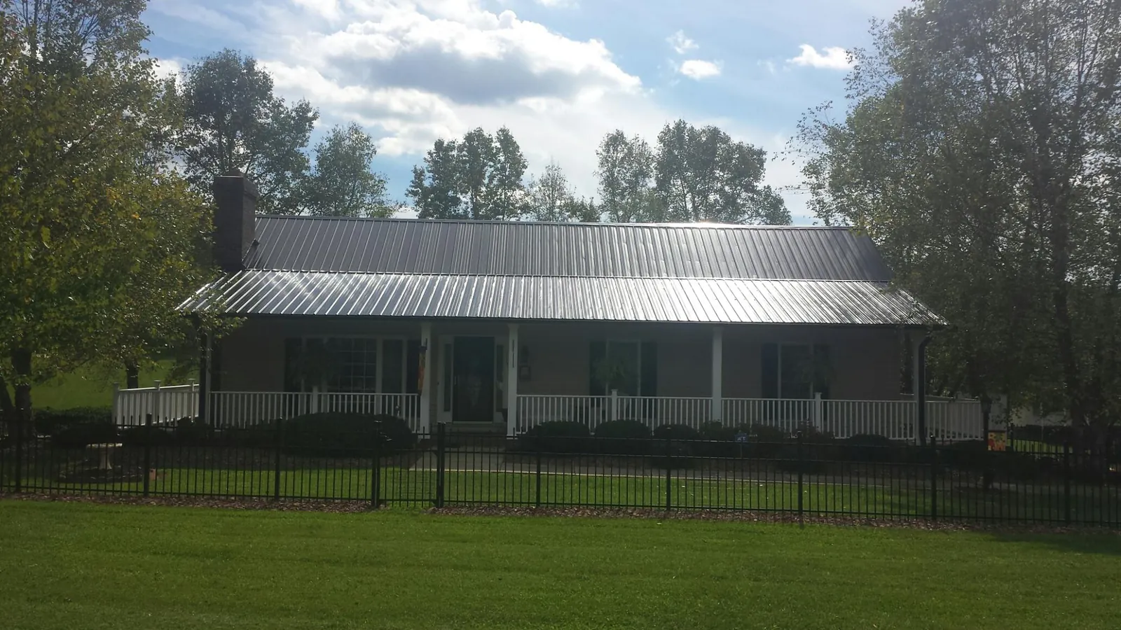 Gray metal roof on a brick ranch with a full width front porch — Gutter Guard Installation work by our crew in Harrodsburg