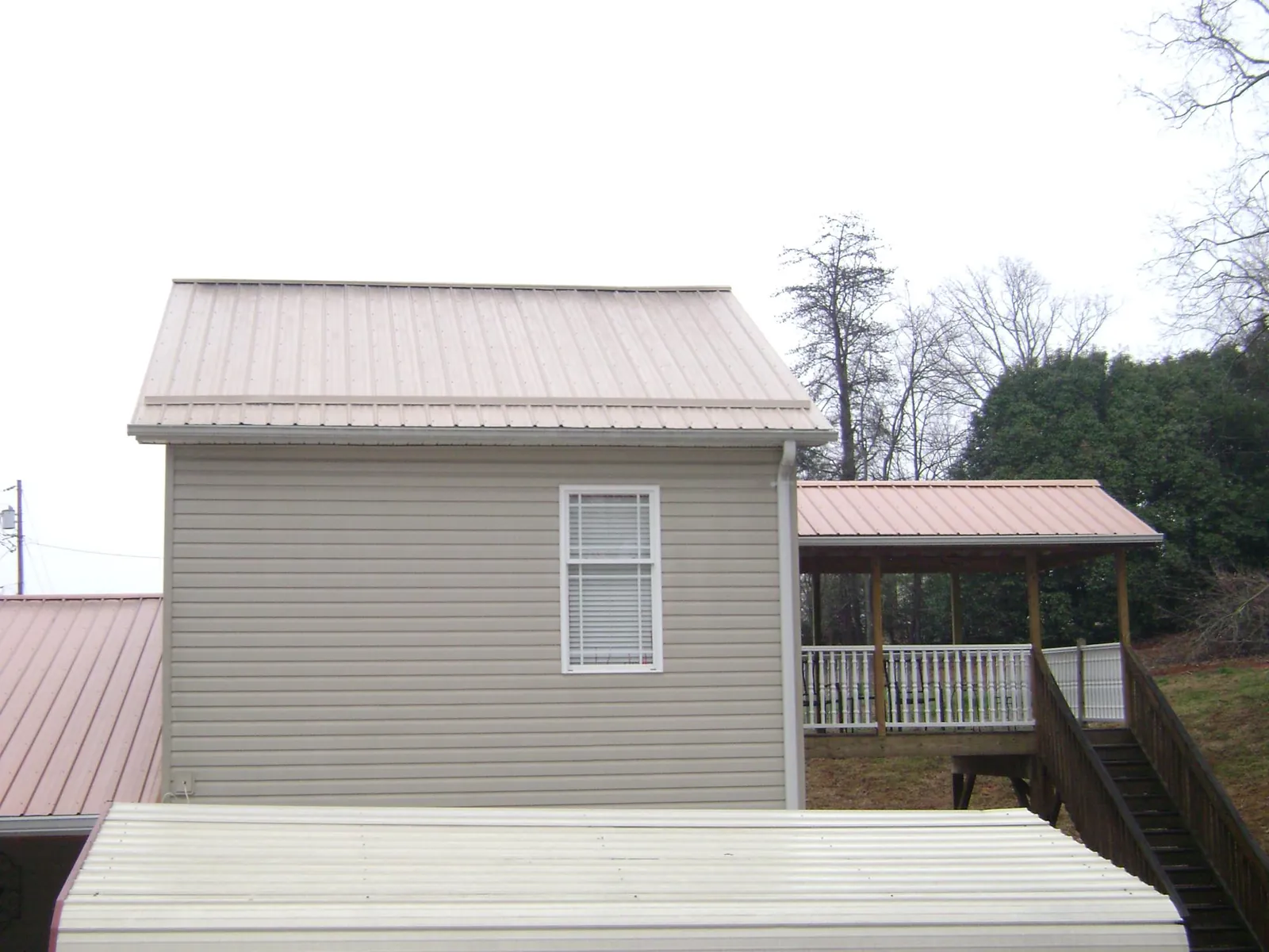 Tan metal roofs on a two story addition and attached porch, from a Roof Replacement job in Harrodsburg