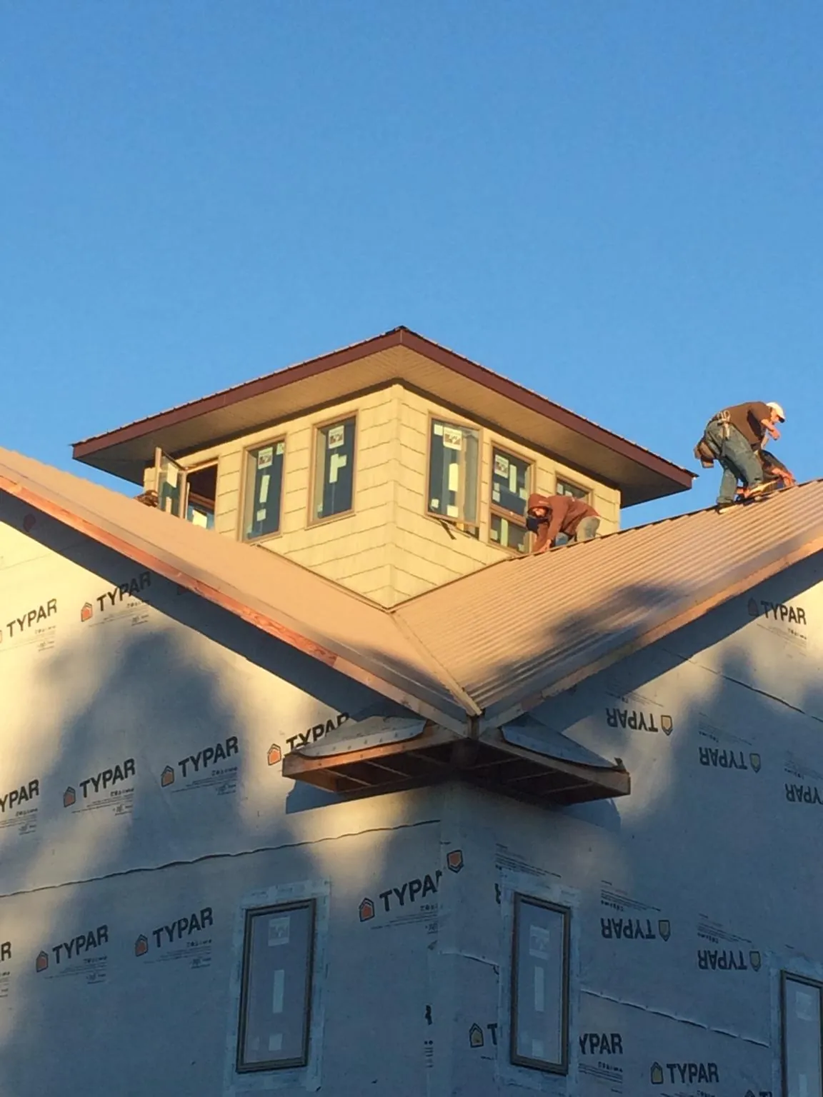 Roofers working around a rooftop cupola on a new metal roof at sunset — Roof Waterproofing in Harrodsburg by Roofing Brothers